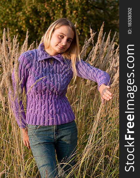 A girl in a lilac pullover and jeans in grass. A girl in a lilac pullover and jeans in grass