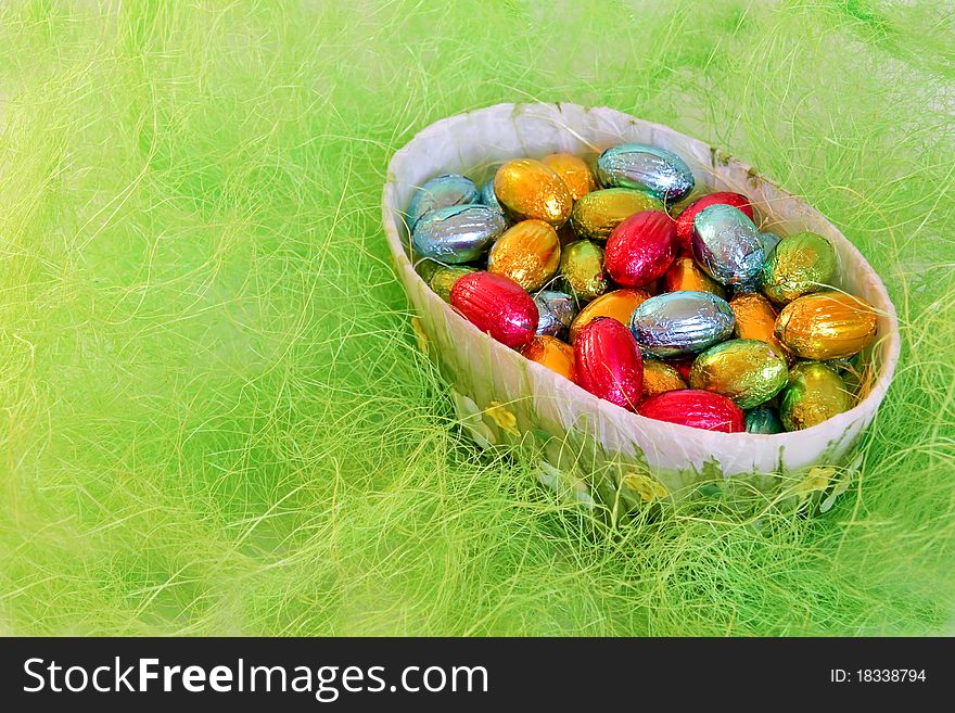 Chocolate eggs in the bowl on the imitation of hay