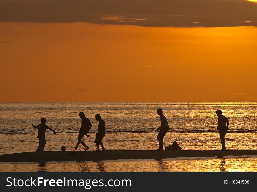 Children with beach football during sunset.