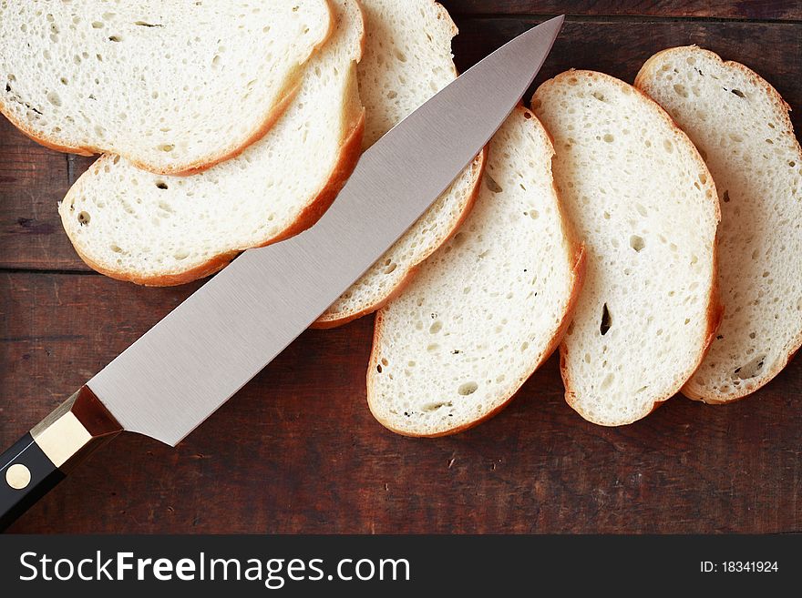 Sliced white bread and kitchen knife on wooden surface. Sliced white bread and kitchen knife on wooden surface