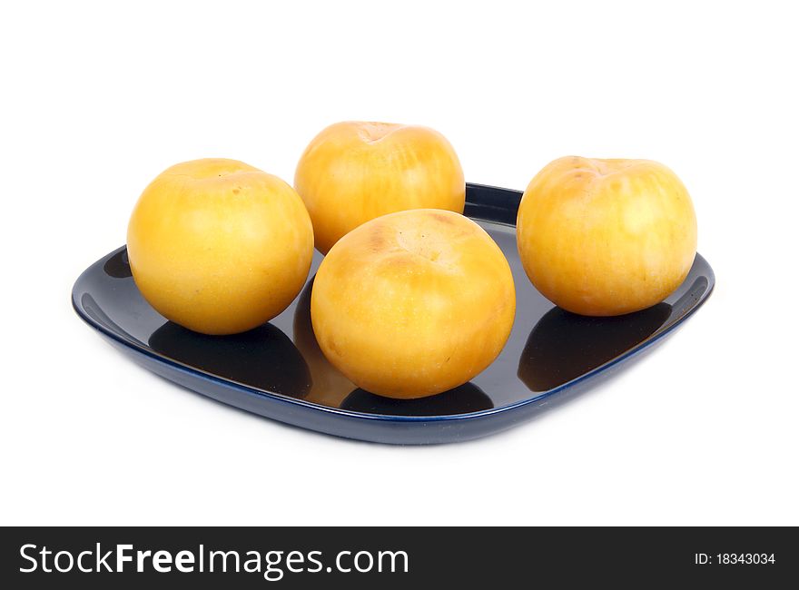 Yellow plums on a dark blue plate, isolated on a white background