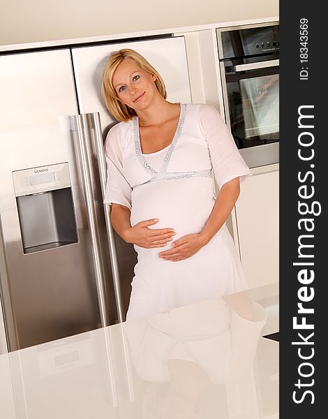 Young and happy pregnant woman standing in the kitchen at home. Young and happy pregnant woman standing in the kitchen at home