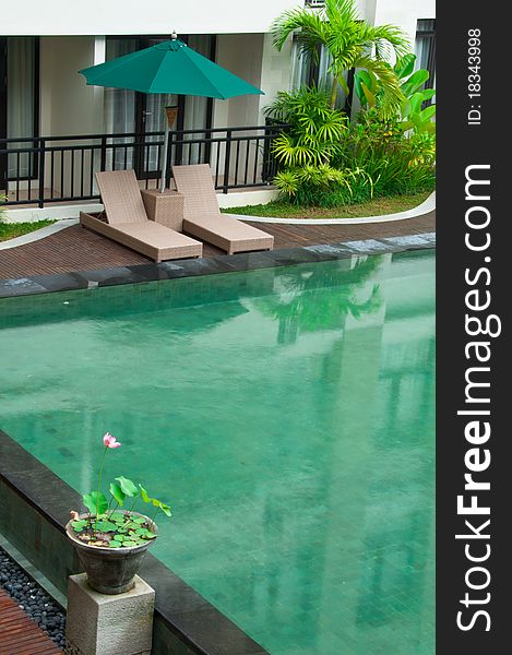 Apartment and residential tropical swimming pool with wicker pool side bed and umbrella