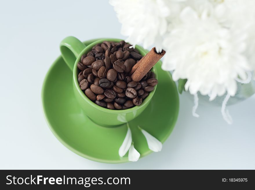 Coffee beans in a green cup on a white background