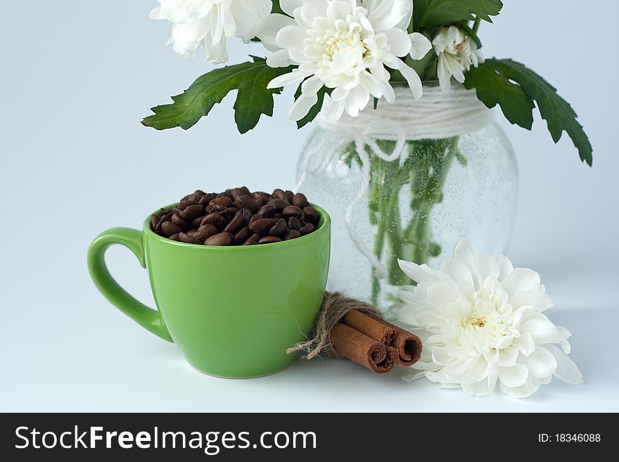 Coffee beans in a green cup on a white background