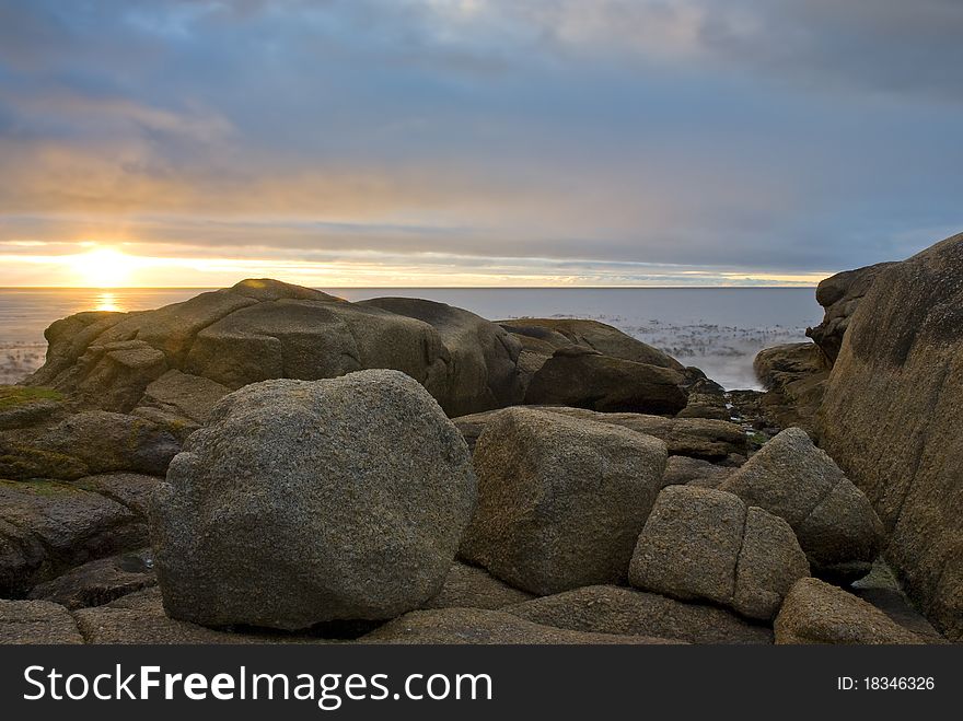 Sun setting over the ocean, with rock formations in the foreground. Sun setting over the ocean, with rock formations in the foreground