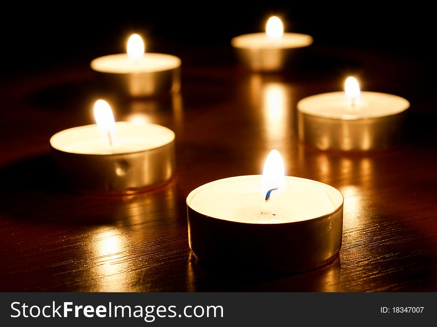 Group of small candles on a dark background.
