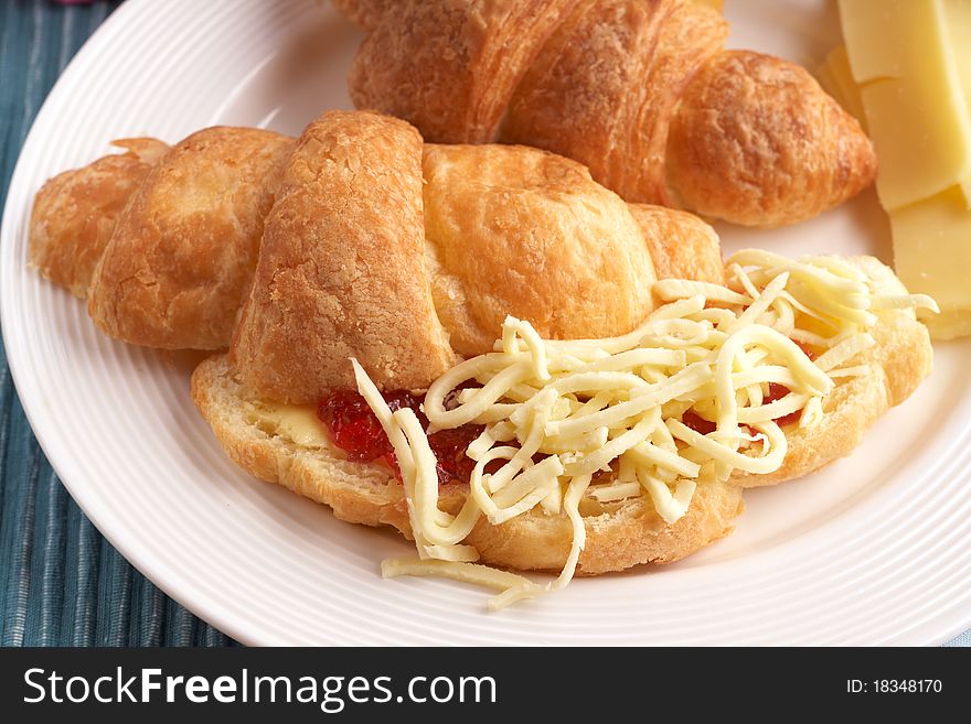 Breakfast plate with freshly baked croissants filled with jam and grated mozzarella cheese. Breakfast plate with freshly baked croissants filled with jam and grated mozzarella cheese