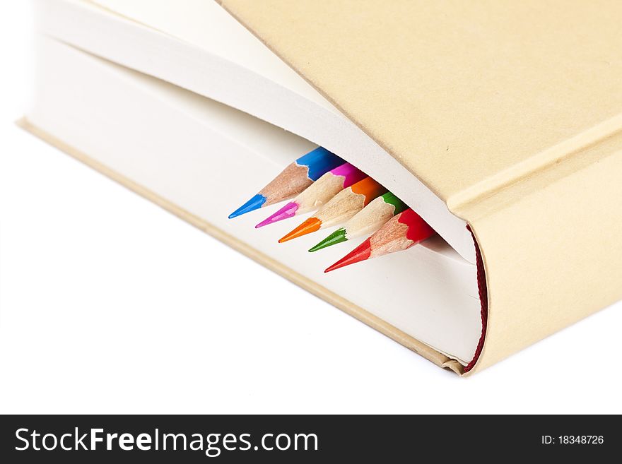 Colorful pencils on closed book on white