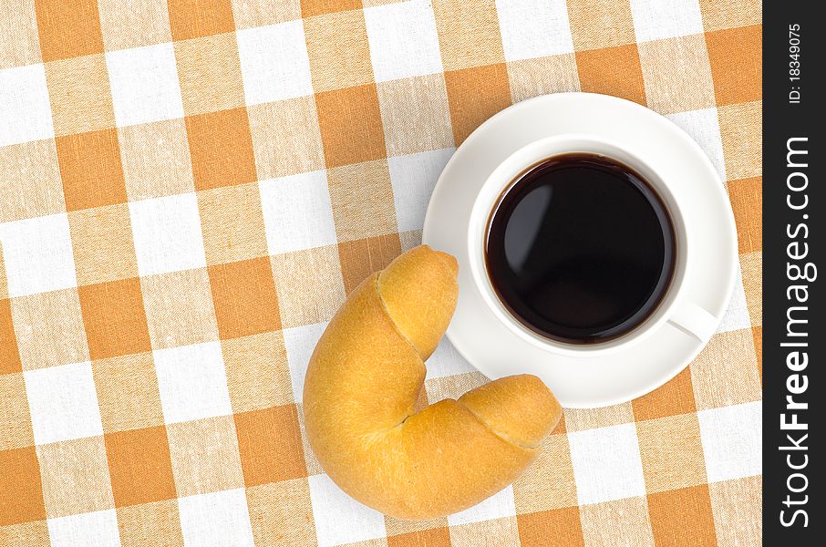 Top view of black coffee cup and croissant on checked tablecloth. Top view of black coffee cup and croissant on checked tablecloth