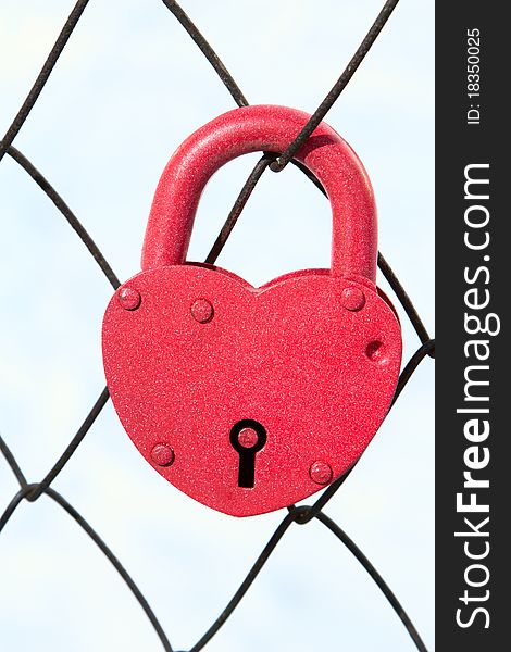 Padlock in form of the heart on net of the fence. Padlock in form of the heart on net of the fence