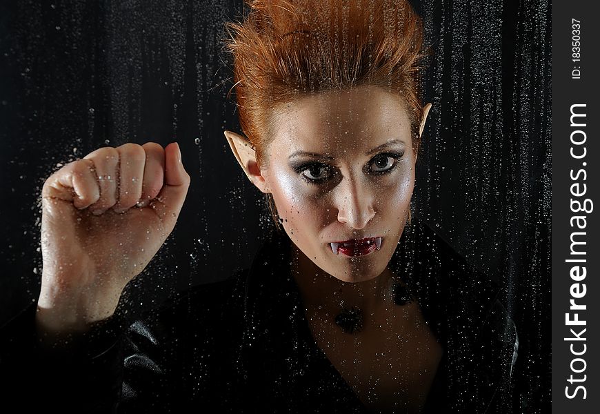 Portrait horrible fashion vampire woman behind rainy window. Portrait horrible fashion vampire woman behind rainy window