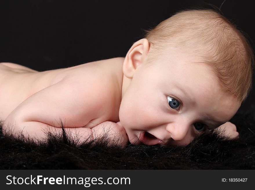 Beautiful three month old baby boy lying on black fur. Beautiful three month old baby boy lying on black fur
