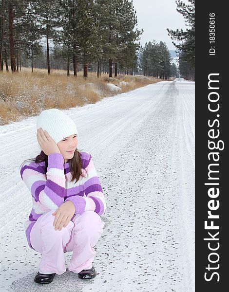 Young girl sitting in the middle of a long isolated road. Young girl sitting in the middle of a long isolated road