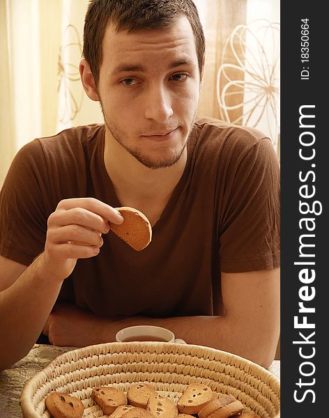 Young Guy With Tea And Rusk In The Kitchen