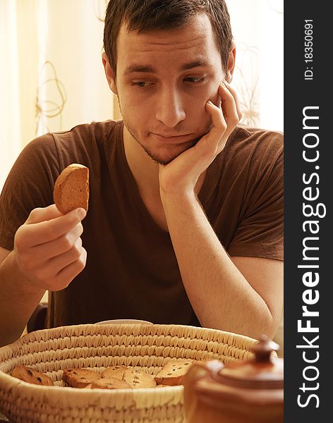 Young guy with tea and rusk in the kitchen