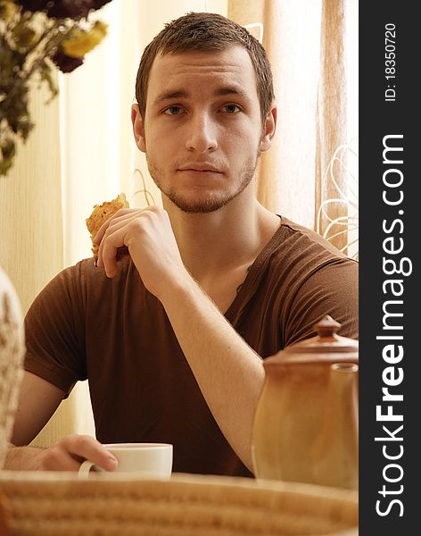 Young Guy With Tea And Cake In The Kitchen