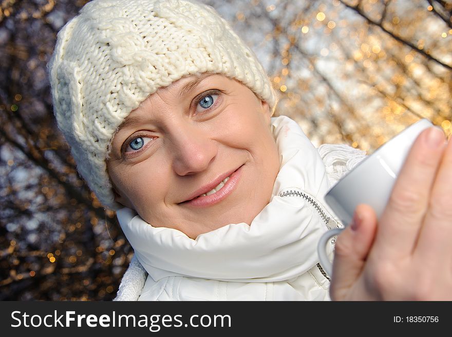 Blue-eyed woman in white, with a mug in his hands, in the winter forest. closeup, portrait