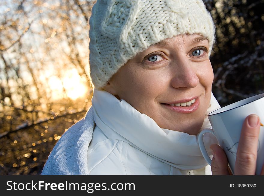 Blue-eyed woman in white, with a mug in his hands, in the winter forest. closeup, portrait