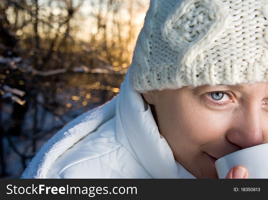 Blue-eyed woman in white, with a mug in his hands, in the winter forest. closeup, portrait