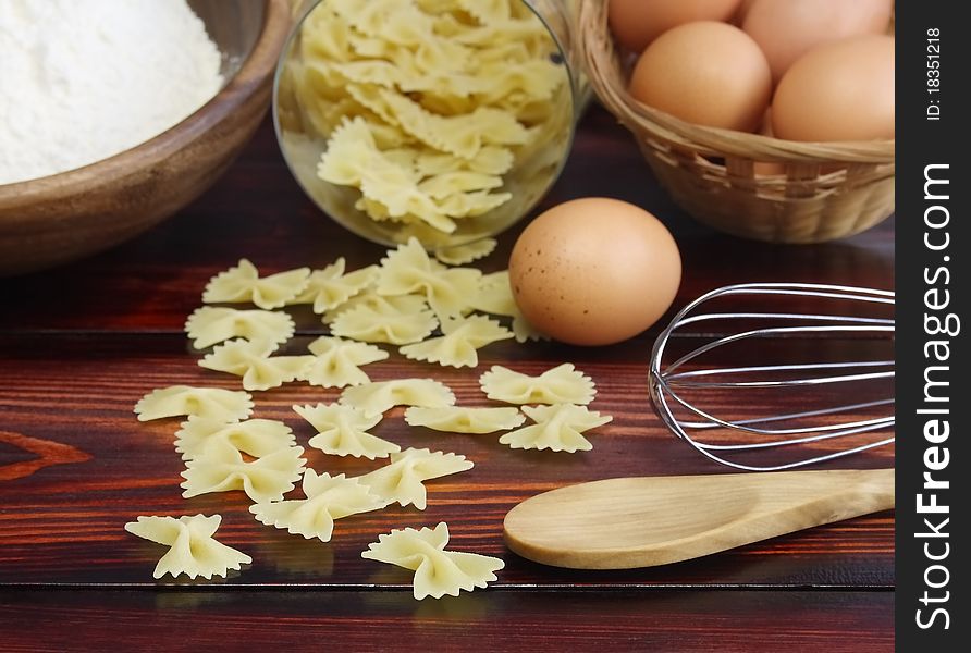 Pasta and components for its preparation on a table. Pasta and components for its preparation on a table.