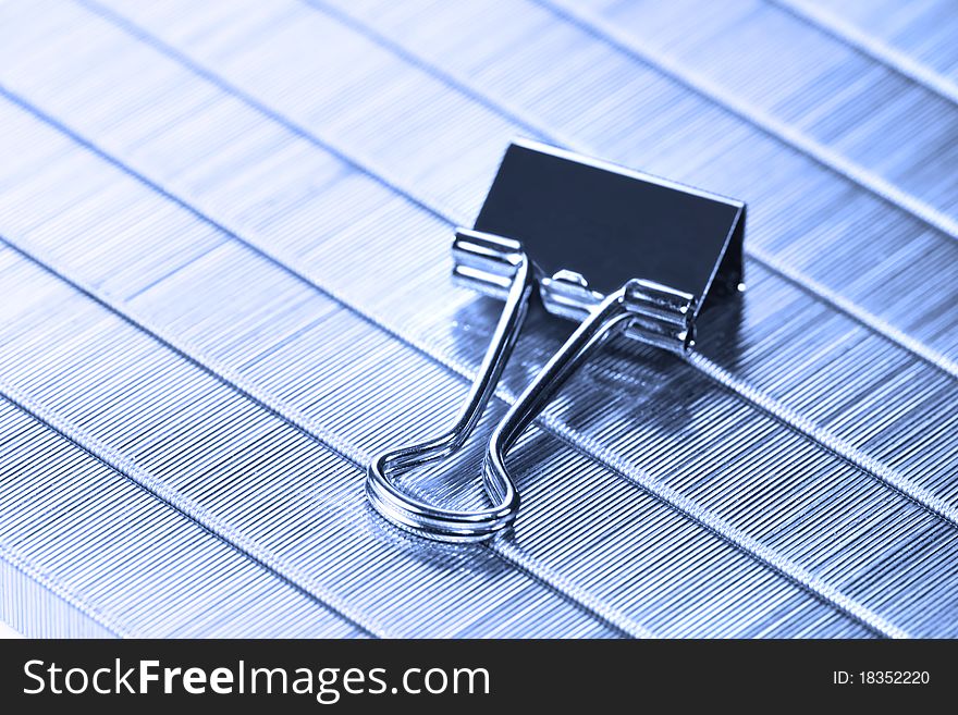 Single paper clip on staples background in blue color tone