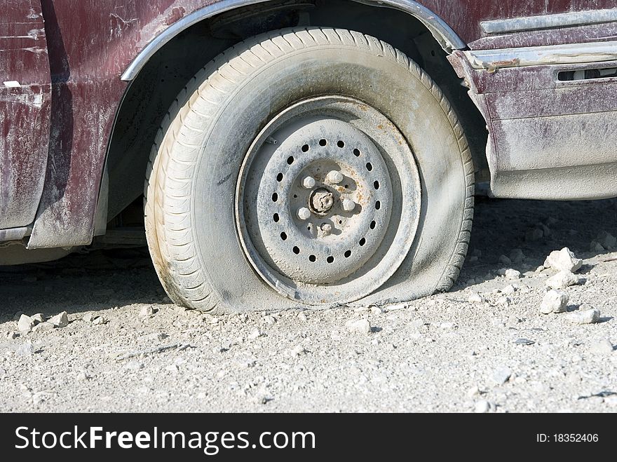 A flat tyre on a red well used car. A flat tyre on a red well used car