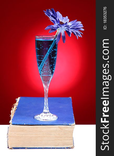 Blue refreshing party drink over blue book isolated on red background. Blue refreshing party drink over blue book isolated on red background.