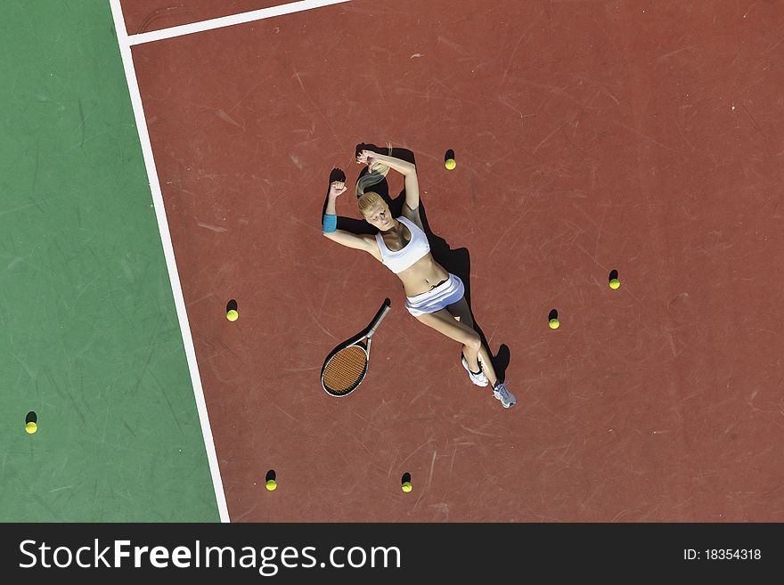 Young fit woman play tennis outdoor on orange tennis field at early morning. Young fit woman play tennis outdoor on orange tennis field at early morning