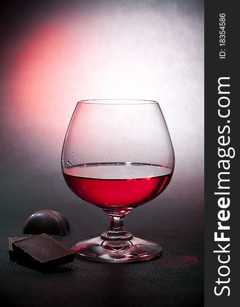 Luxury red liqueur on crystal balloon glass and milk chocolate. Luxury red liqueur on crystal balloon glass and milk chocolate