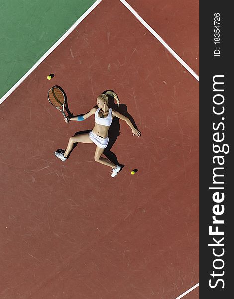 Young fit woman play tennis outdoor on orange tennis field at early morning. Young fit woman play tennis outdoor on orange tennis field at early morning