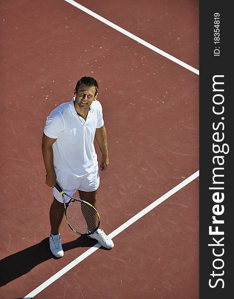 Young man play tennis outdoor on orange tennis field at early morning