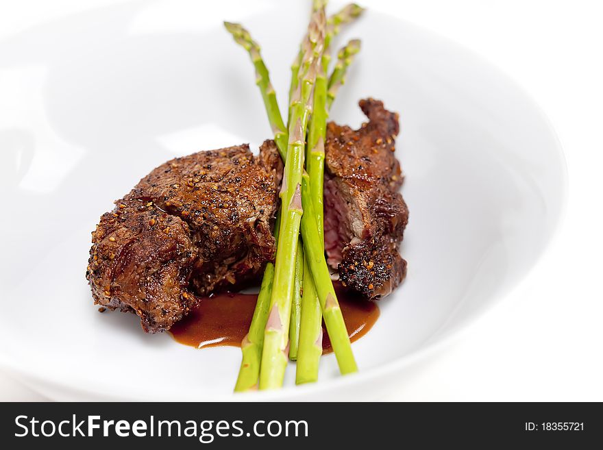 A prime Fillet Mignon grilled to perfection au poive with peppercorns and garnished with fresh asparagus. A prime Fillet Mignon grilled to perfection au poive with peppercorns and garnished with fresh asparagus.
