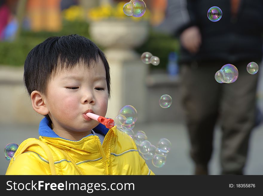 Child blowing soap bubbles in a park. Child blowing soap bubbles in a park