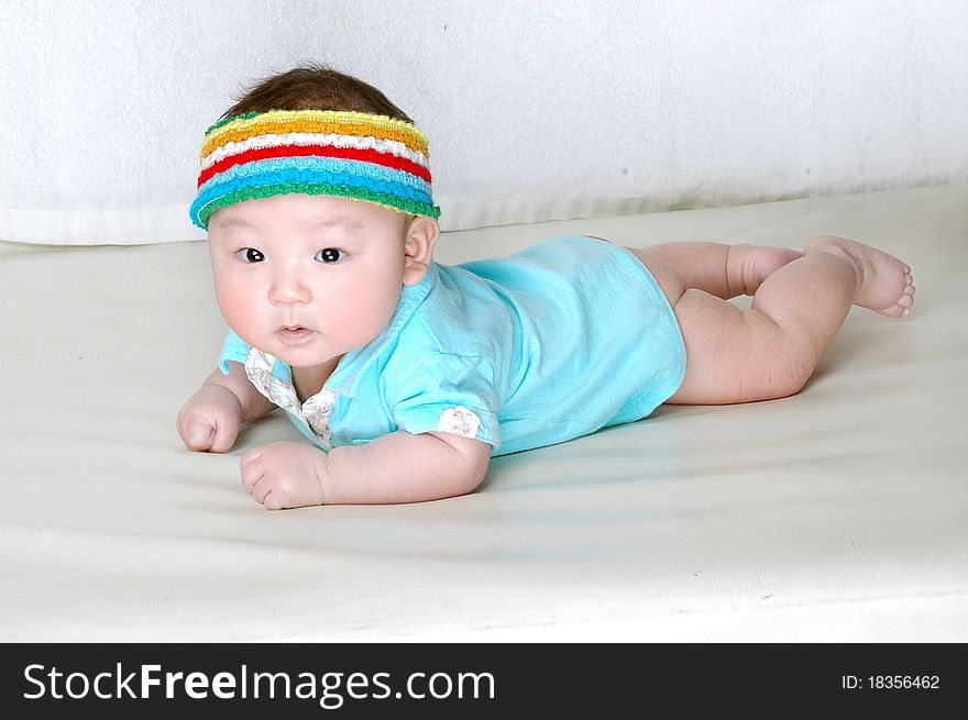 A cute baby is laying on a bed and wearing a colorful cap on his head. A cute baby is laying on a bed and wearing a colorful cap on his head