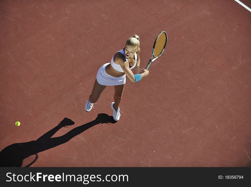 Young fit woman play tennis outdoor on orange tennis field at early morning. Young fit woman play tennis outdoor on orange tennis field at early morning