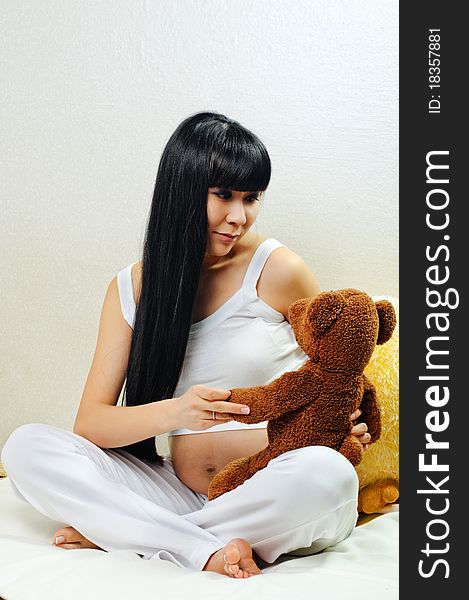 Young pregnant woman plays with bear toy. Young pregnant woman plays with bear toy