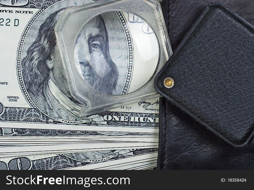 Leather wallet and magnifier on a dollars background. Leather wallet and magnifier on a dollars background