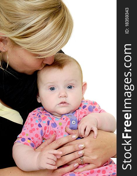 Mother is looking down on her sweet baby while kissing her. Taken on a white background. Mother is looking down on her sweet baby while kissing her. Taken on a white background.