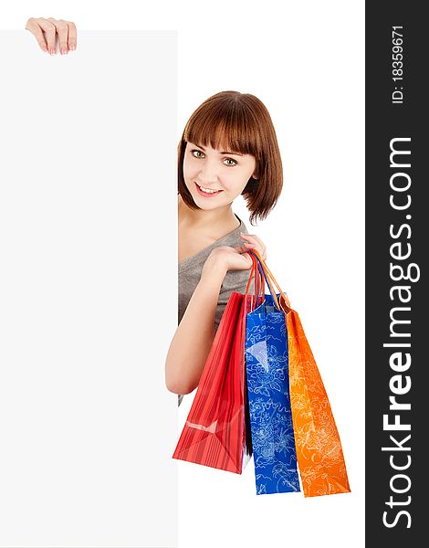 Smiling woman with shopping bags holding blank billboard sign, isolated on white