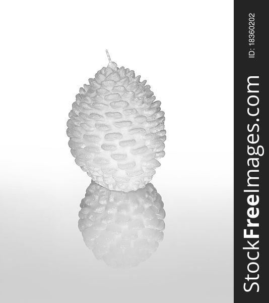 Photograph of a white decorative candle shaped as a pine cone against white background with reflection in foreground. Photograph of a white decorative candle shaped as a pine cone against white background with reflection in foreground