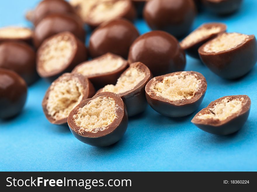 Chocolate balls and halves with crisp filling on blue background