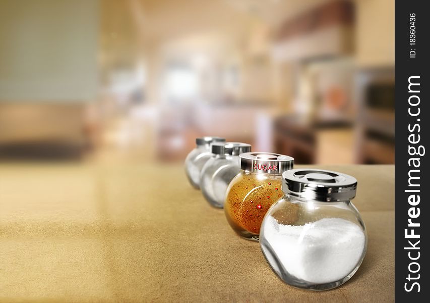 Shallow depth of field photo of a series of spice jars in modern kitchen with focus on a decorative brown sugar container