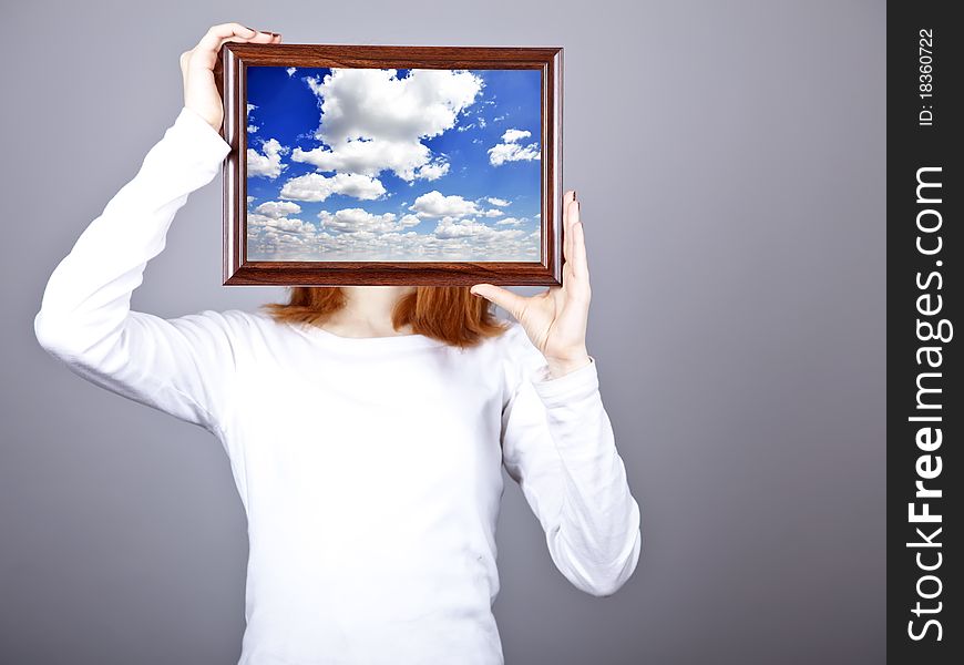 Girl keep frame with clouds sky inside. Studio shot.