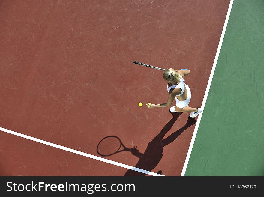 Young fit woman play tennis outdoor on orange tennis field at early morning. Young fit woman play tennis outdoor on orange tennis field at early morning