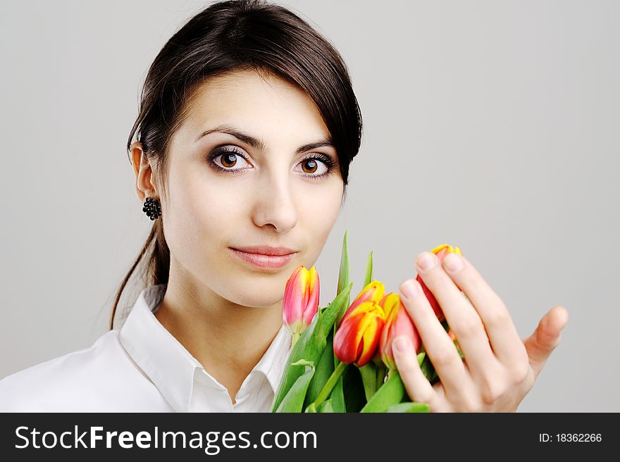 An image of young woman holding a bunch of orange tulips. An image of young woman holding a bunch of orange tulips