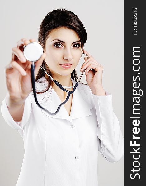 Young female doctor holding stethoscope to camera