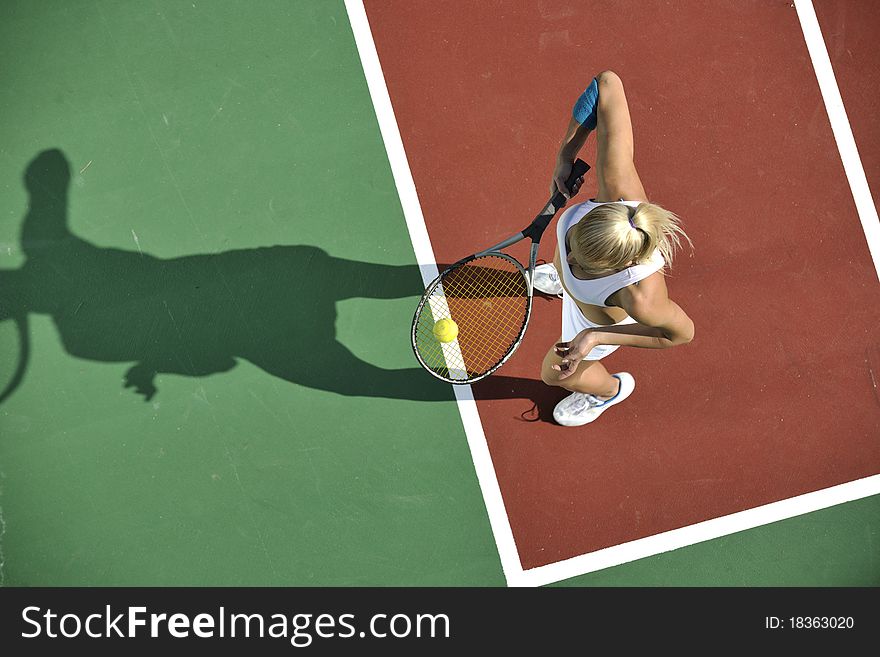 Young fit woman play tennis outdoor on orange tennis field at early morning. Young fit woman play tennis outdoor on orange tennis field at early morning