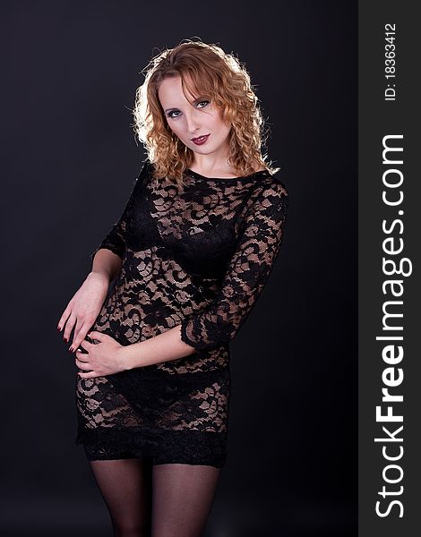 Young gorgeous model in a lace dress, a black background