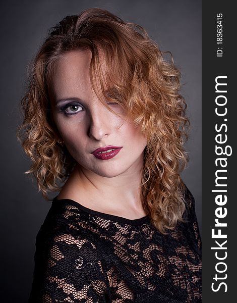 Young gorgeous model in a lace dress, a black background